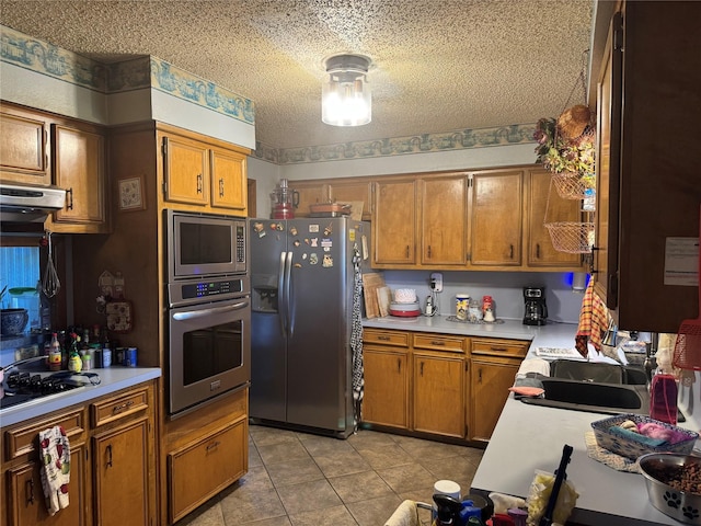 kitchen featuring appliances with stainless steel finishes, a textured ceiling, light tile patterned floors, and sink