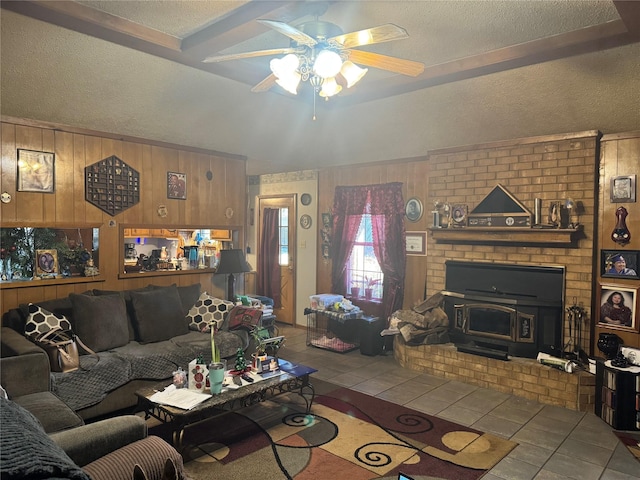 tiled living room featuring ceiling fan, wood walls, a wood stove, and a textured ceiling