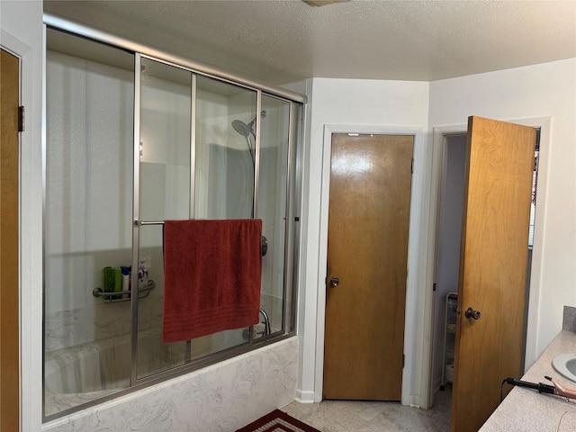 bathroom featuring vanity, enclosed tub / shower combo, and a textured ceiling