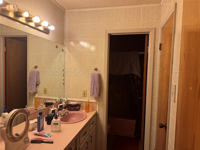 bathroom with a textured ceiling, vanity, toilet, and tile walls