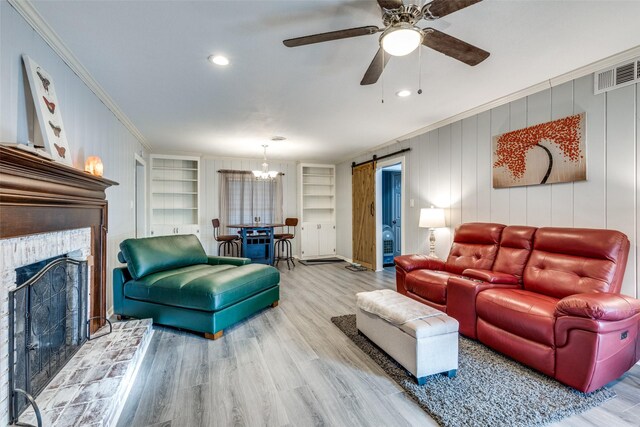 living room featuring built in shelves, a barn door, crown molding, and wood-type flooring