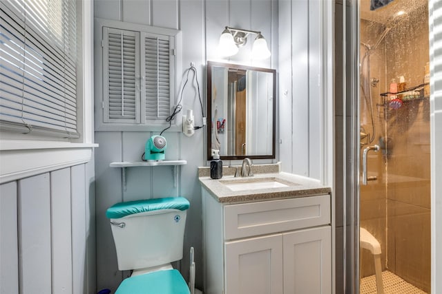 bathroom featuring vanity, a shower with shower door, and toilet