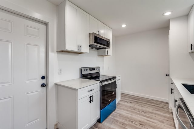 kitchen with white cabinets, stainless steel appliances, and light hardwood / wood-style floors