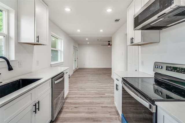 kitchen with sink, ceiling fan, appliances with stainless steel finishes, white cabinetry, and light wood-type flooring