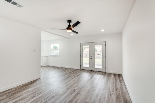 empty room with ceiling fan, light wood-type flooring, and french doors