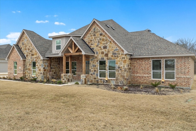 craftsman house featuring roof with shingles, brick siding, stone siding, and a front yard