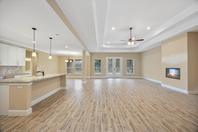 unfurnished living room with baseboards, a glass covered fireplace, recessed lighting, and light wood-style flooring