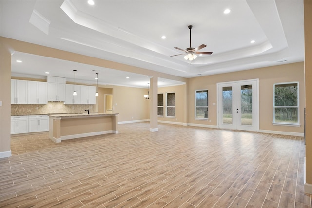 unfurnished living room featuring crown molding, a ceiling fan, and a raised ceiling