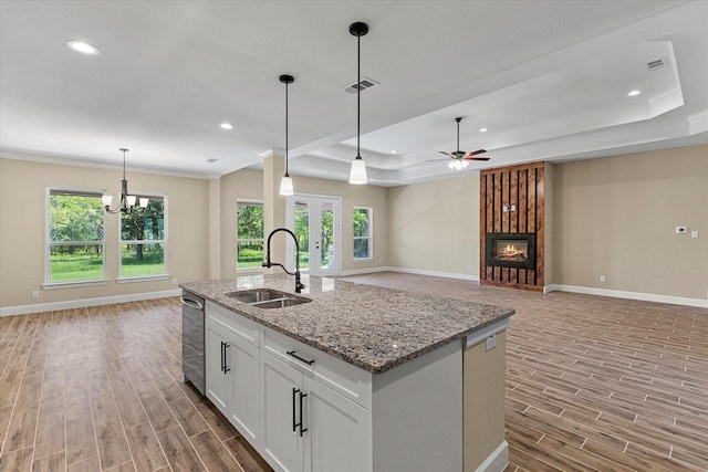 kitchen with baseboards, a raised ceiling, light wood finished floors, and a sink