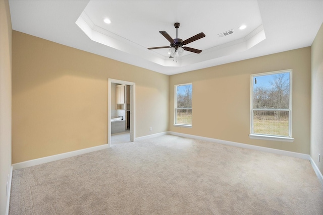 empty room featuring visible vents, ceiling fan, light carpet, a raised ceiling, and baseboards