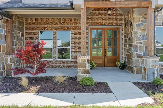 view of exterior entry with stone siding, french doors, and brick siding