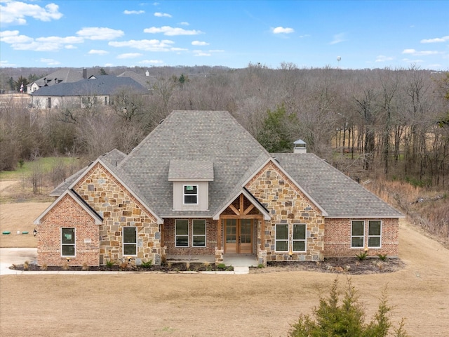 craftsman-style house featuring covered porch, stone siding, brick siding, and a shingled roof