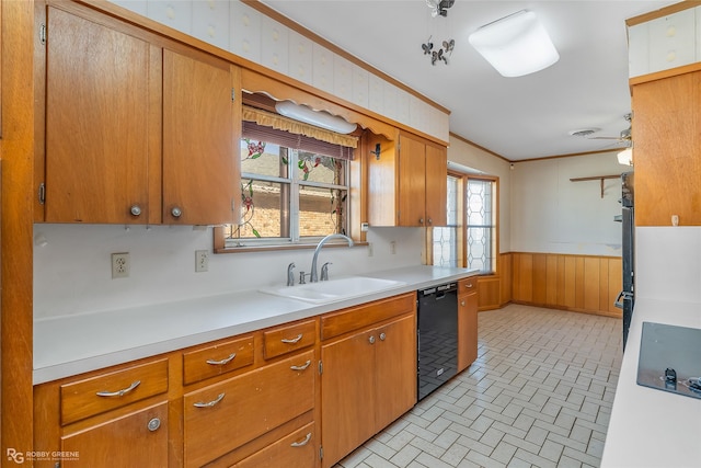 kitchen with ornamental molding, ceiling fan, wooden walls, sink, and dishwasher