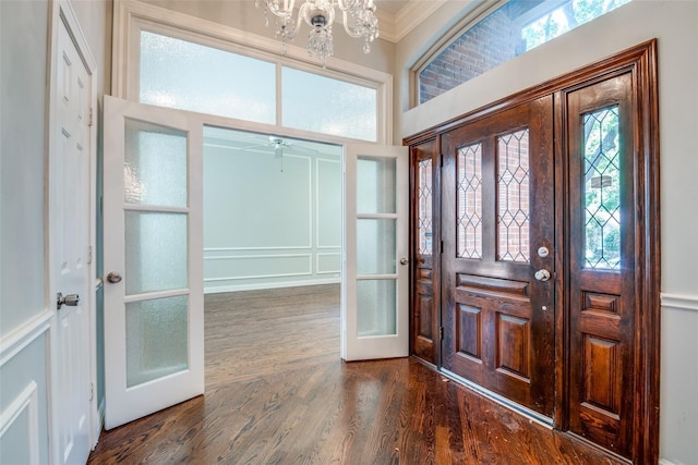 foyer entrance featuring dark hardwood / wood-style flooring, crown molding, french doors, and ceiling fan with notable chandelier