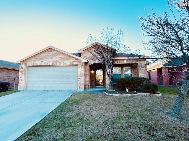 ranch-style house featuring a garage, brick siding, driveway, and a front lawn