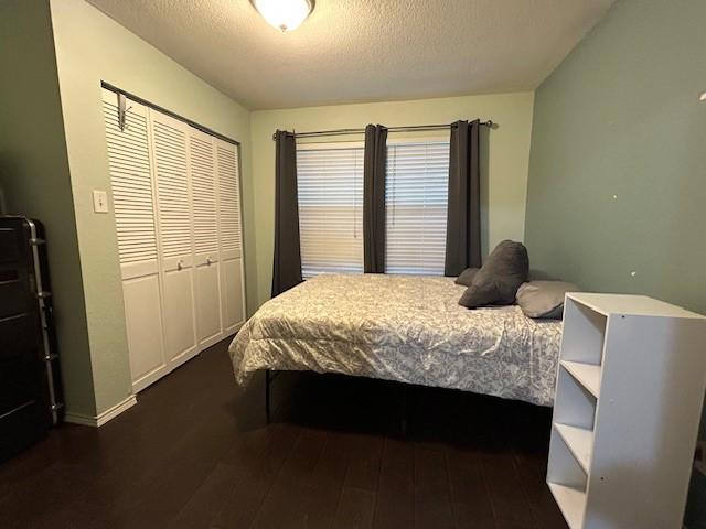 bedroom with a textured ceiling, a closet, and dark wood finished floors