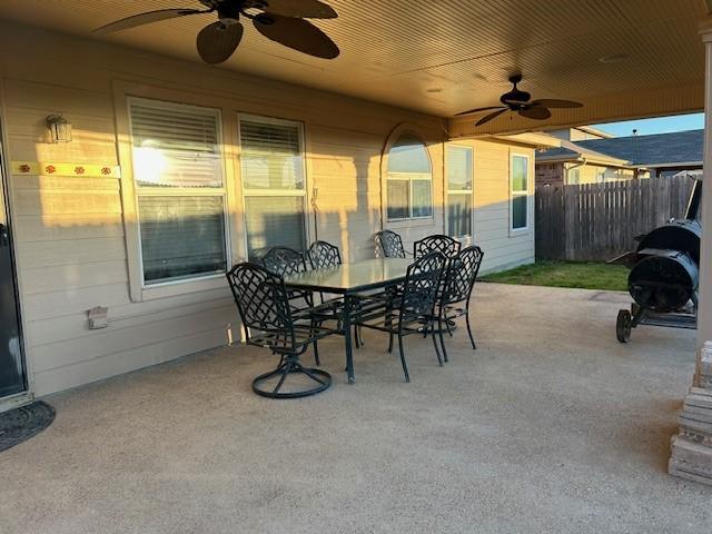 view of patio featuring ceiling fan, outdoor dining area, and fence