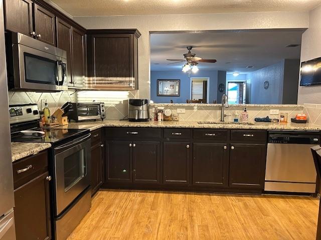 kitchen featuring tasteful backsplash, appliances with stainless steel finishes, a sink, and light wood-style floors