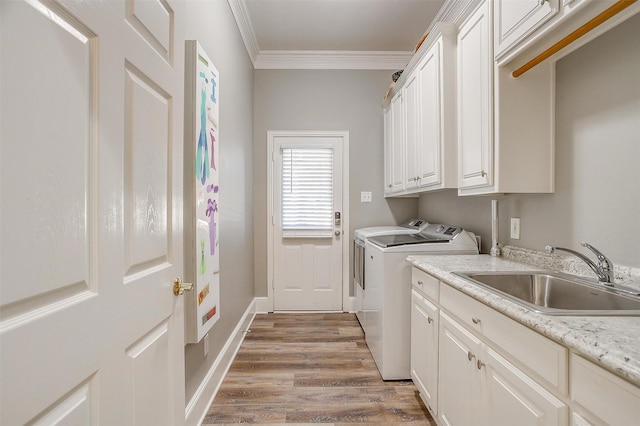 laundry room with hardwood / wood-style floors, cabinets, crown molding, washer and dryer, and sink