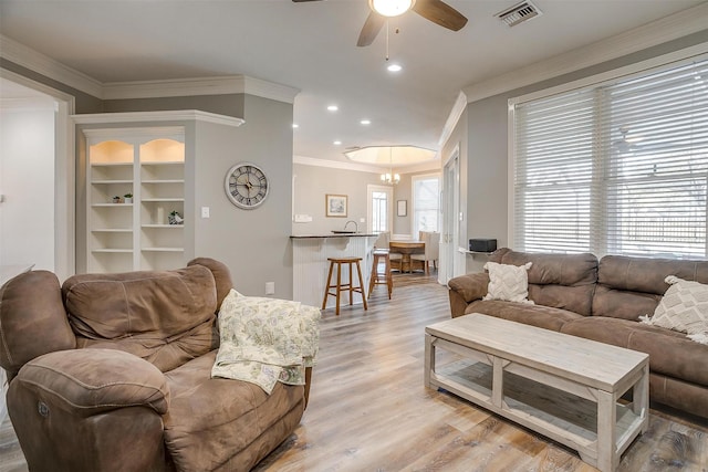 living room featuring light wood-type flooring, crown molding, and ceiling fan with notable chandelier