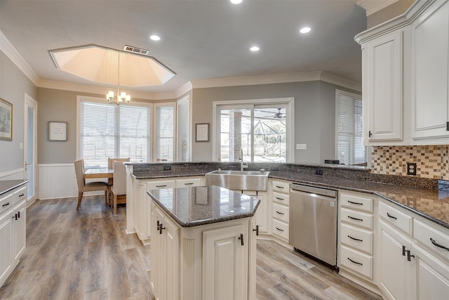 kitchen with kitchen peninsula, stainless steel dishwasher, pendant lighting, light hardwood / wood-style floors, and sink