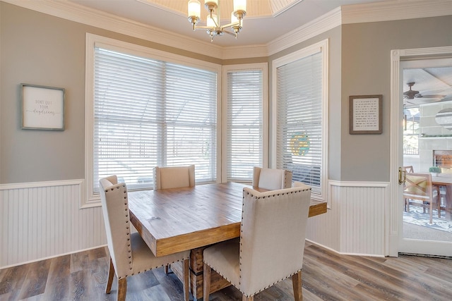 dining room with a healthy amount of sunlight, hardwood / wood-style floors, crown molding, and ceiling fan with notable chandelier