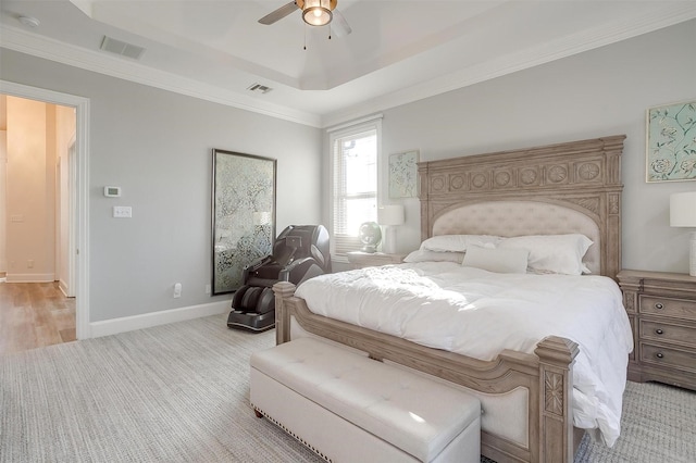 bedroom featuring ceiling fan, light hardwood / wood-style floors, crown molding, and a tray ceiling