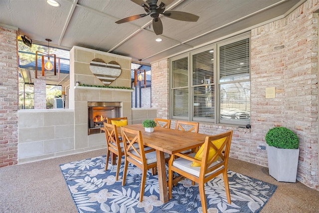 exterior space with ceiling fan, a tile fireplace, and brick wall