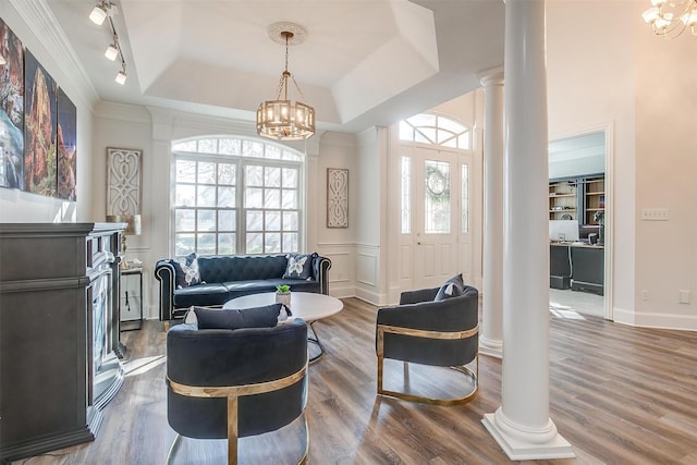 living room with ornate columns, hardwood / wood-style flooring, a chandelier, and a tray ceiling