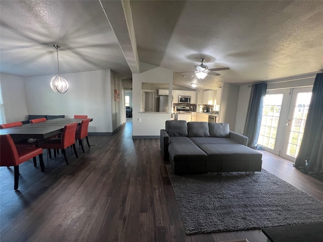 living room featuring a textured ceiling, dark wood-style flooring, ceiling fan with notable chandelier, and baseboards