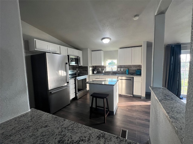 kitchen with appliances with stainless steel finishes, a sink, a breakfast bar, and white cabinets