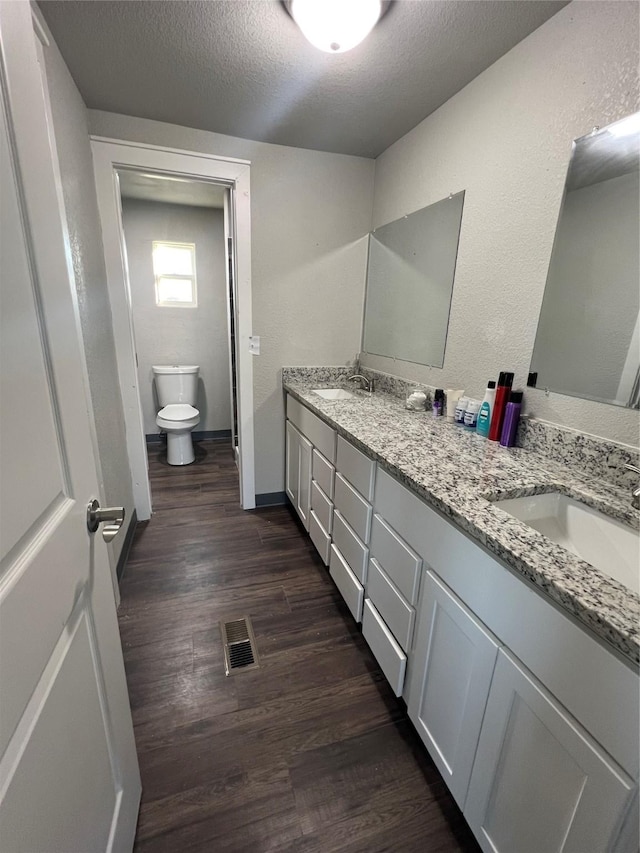 full bath featuring a textured ceiling, wood finished floors, a sink, and visible vents