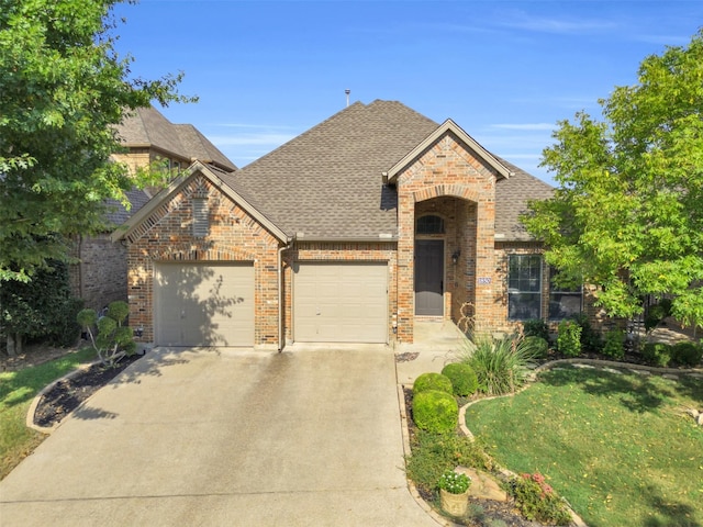 view of front of property featuring driveway, a shingled roof, an attached garage, and brick siding