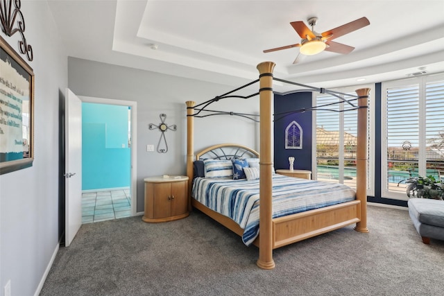 bedroom featuring carpet flooring, a tray ceiling, and ceiling fan