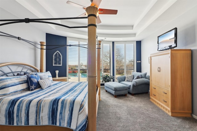 bedroom with carpet flooring, a raised ceiling, and ceiling fan