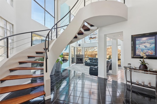 stairs with tile patterned flooring and a towering ceiling