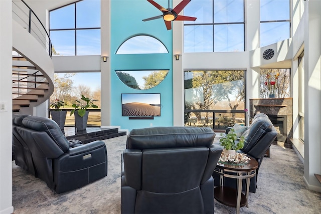 interior space with ceiling fan, a wealth of natural light, a towering ceiling, and a high end fireplace