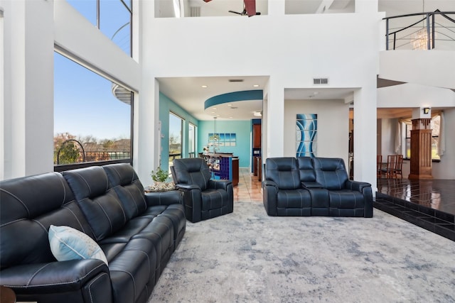 living room with tile patterned floors, ceiling fan, and a towering ceiling