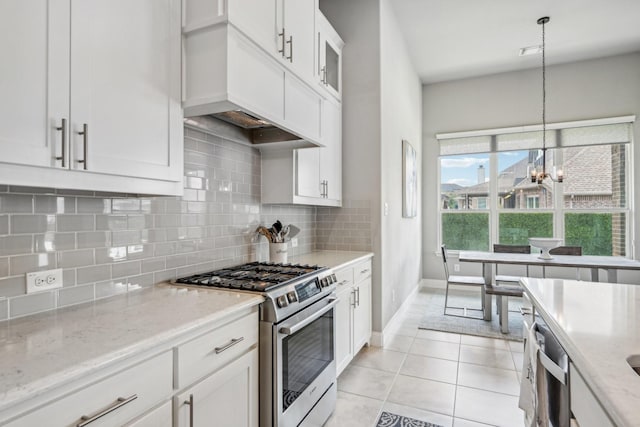 kitchen featuring white cabinetry, light stone counters, a chandelier, light tile patterned floors, and appliances with stainless steel finishes