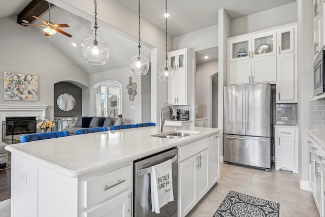 kitchen with a center island with sink, lofted ceiling with beams, white cabinets, sink, and stainless steel appliances