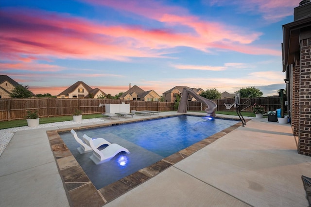 pool at dusk with a water slide and a patio