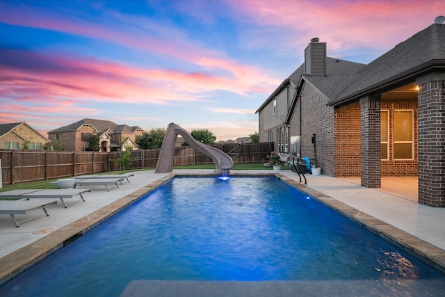 pool at dusk featuring a water slide