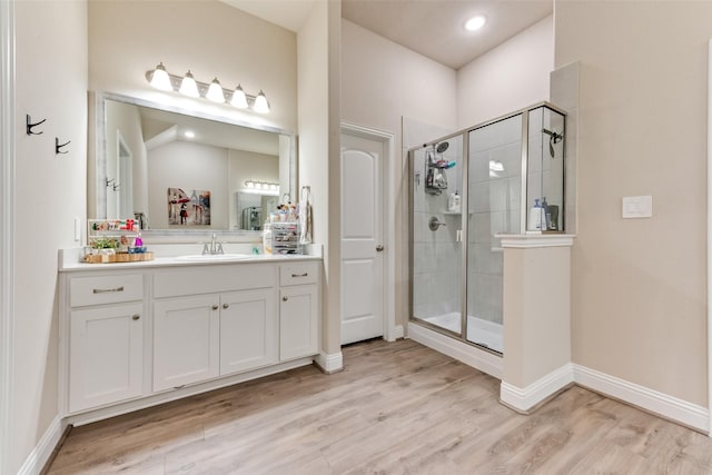 bathroom with hardwood / wood-style floors, vanity, and a shower with door