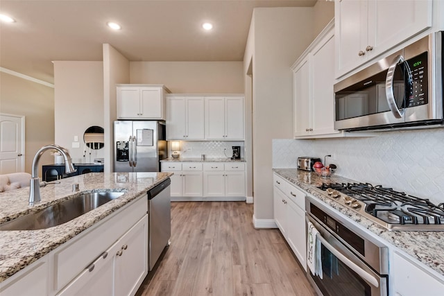 kitchen with light stone countertops, stainless steel appliances, white cabinetry, and sink