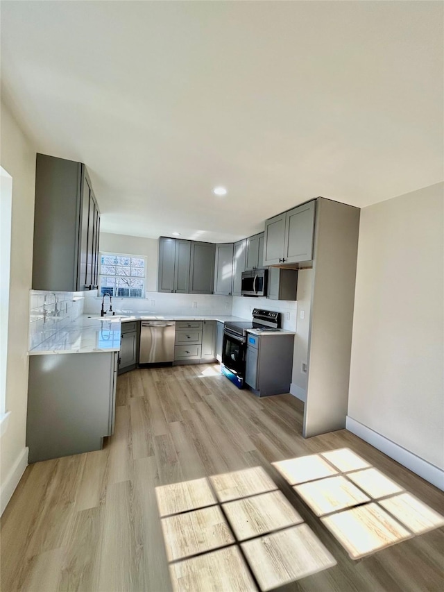 kitchen featuring gray cabinets, sink, light wood-type flooring, and appliances with stainless steel finishes