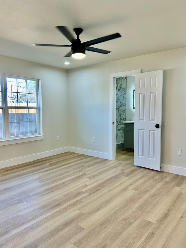 unfurnished bedroom featuring ceiling fan, light wood-type flooring, and connected bathroom