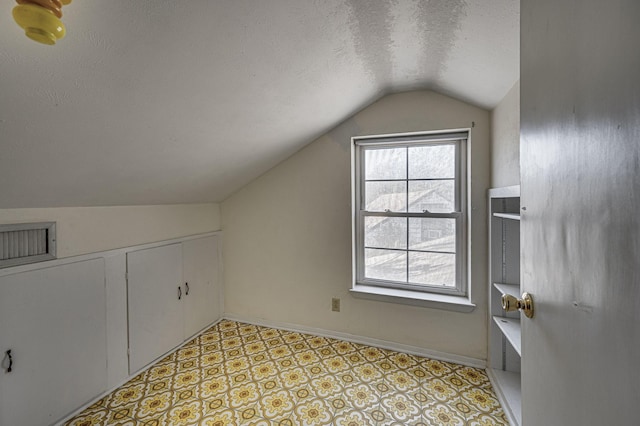 additional living space featuring lofted ceiling and a textured ceiling