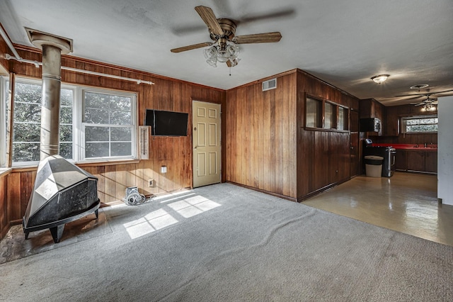 interior space featuring ceiling fan, wood walls, and sink