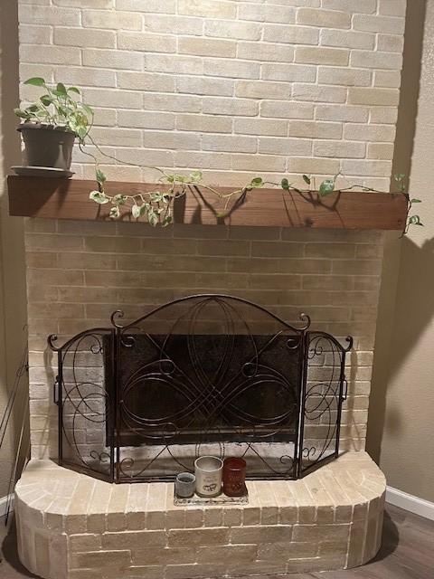 interior details with wood-type flooring and a brick fireplace