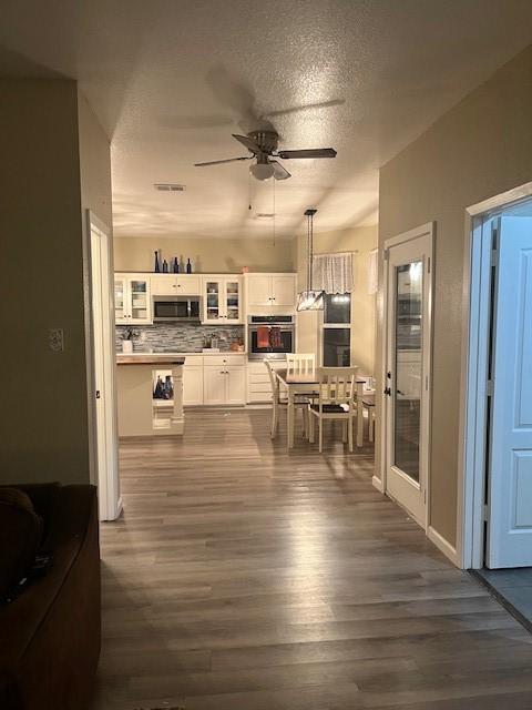 dining room with ceiling fan, dark wood-type flooring, and a textured ceiling